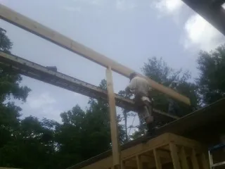 Carpenter setting a ridge beam over a new addition frame — Ice Dam Removal by Roofing Brothers in Lodge