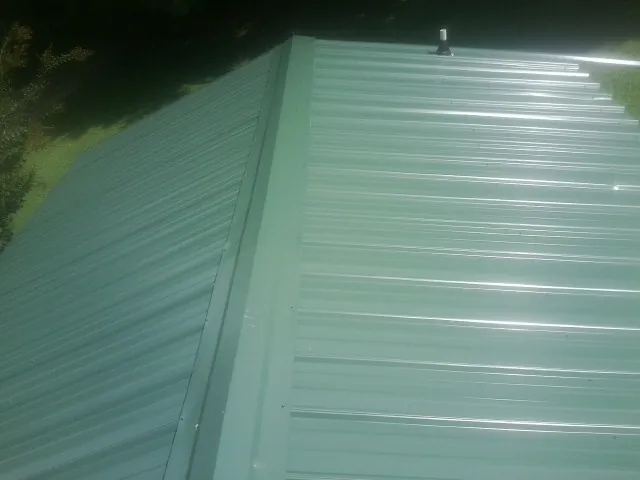 New green metal panels meeting at the ridge of a roof — Flat Roof Repair work by our crew in Lodge