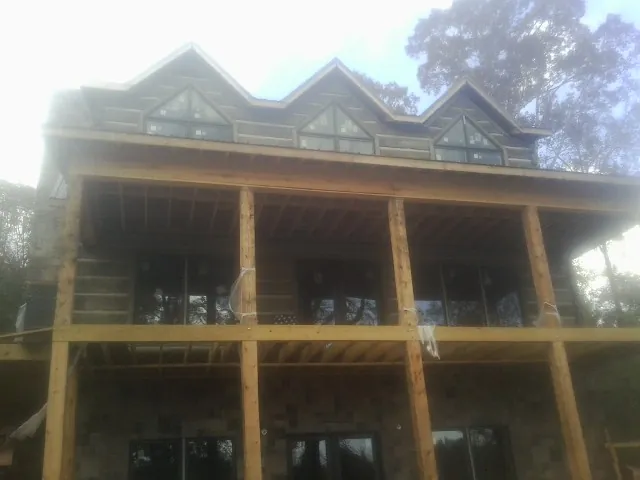 Dormers and porch framing on a large log home under construction — Roof Coating work by our crew in Lodge