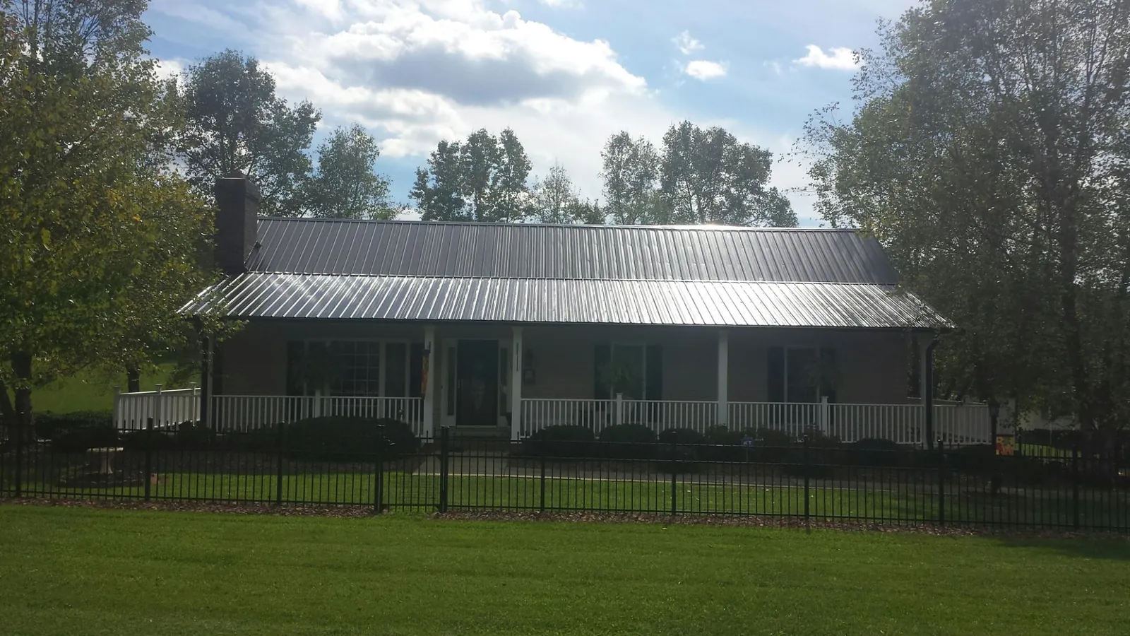 Gray metal roof on a brick ranch with a full width front porch — Gutter Guard Installation work by our crew in Lodge