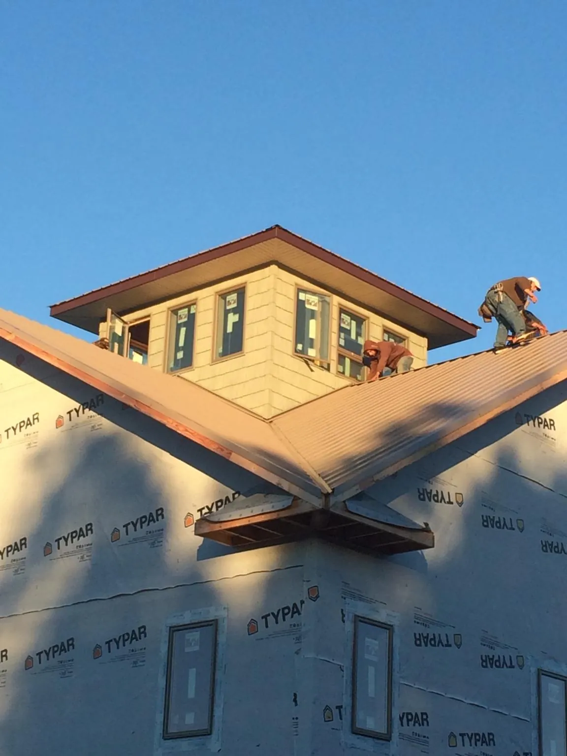 Roofers working around a rooftop cupola on a new metal roof at sunset — Roof Waterproofing in Lodge by Roofing Brothers